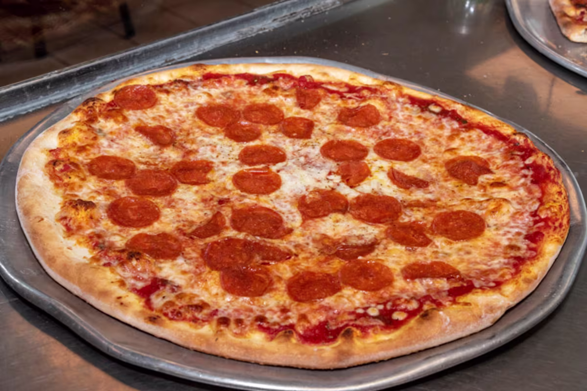 A whole New York style pepperoni pizza on a metal pan
